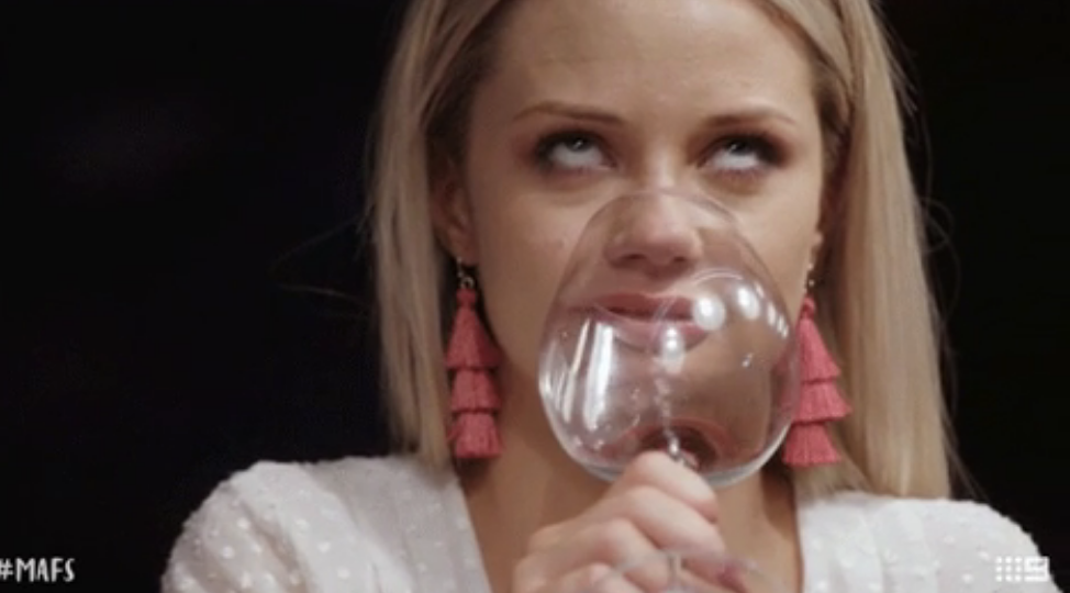 a woman rolling her eyes and drinking wine