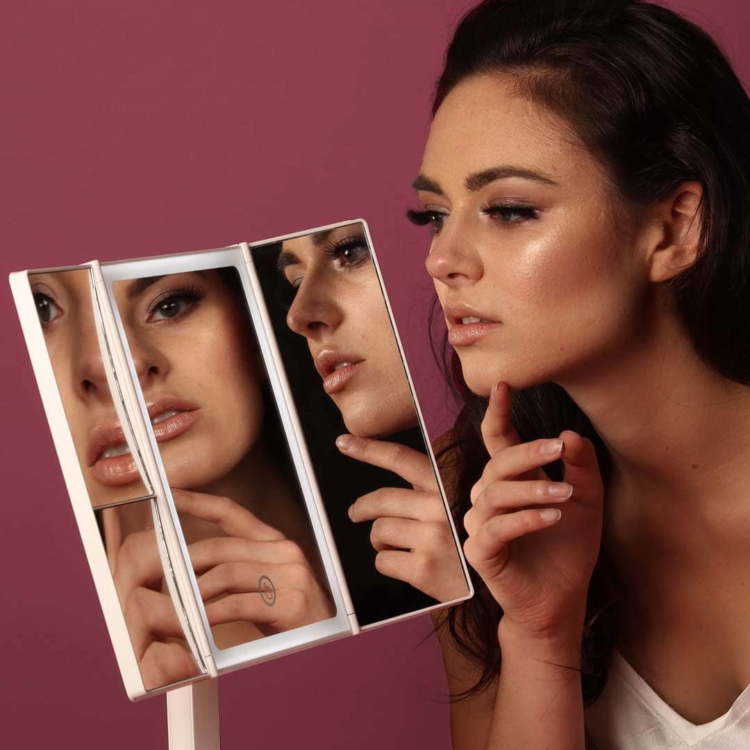 a person looking at themselves in the tri-fold mirror