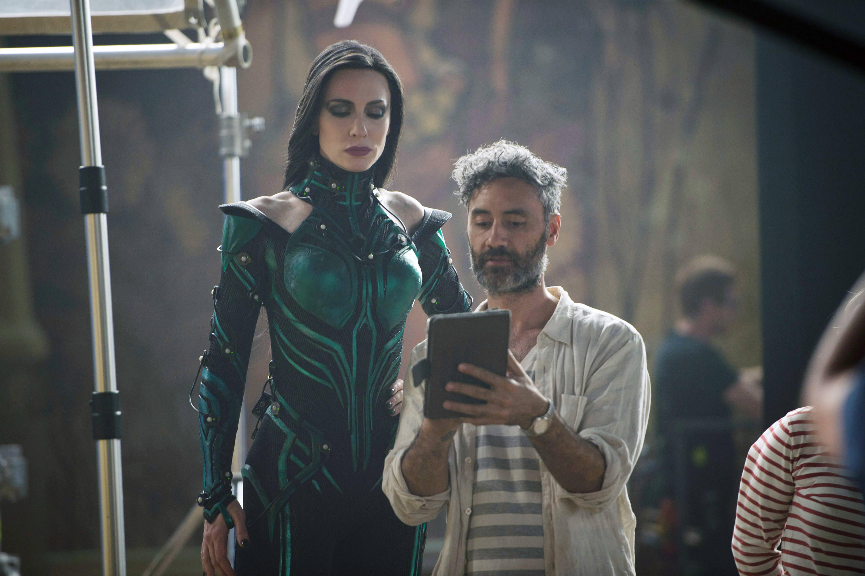 Cate Blanchett looking at a ipad that director Taika Waititi shows her on set