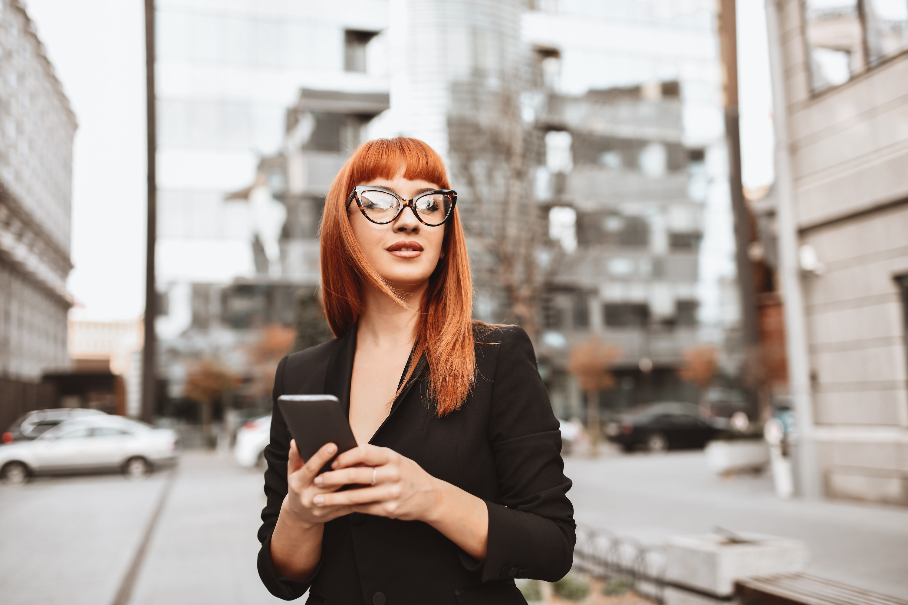 A red-headed woman holding her phone