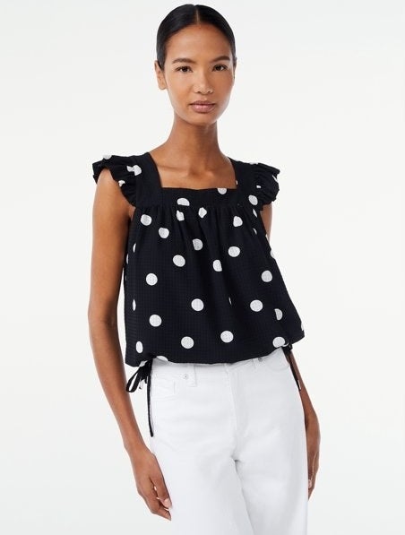 Model wearing black and white top with white jeans