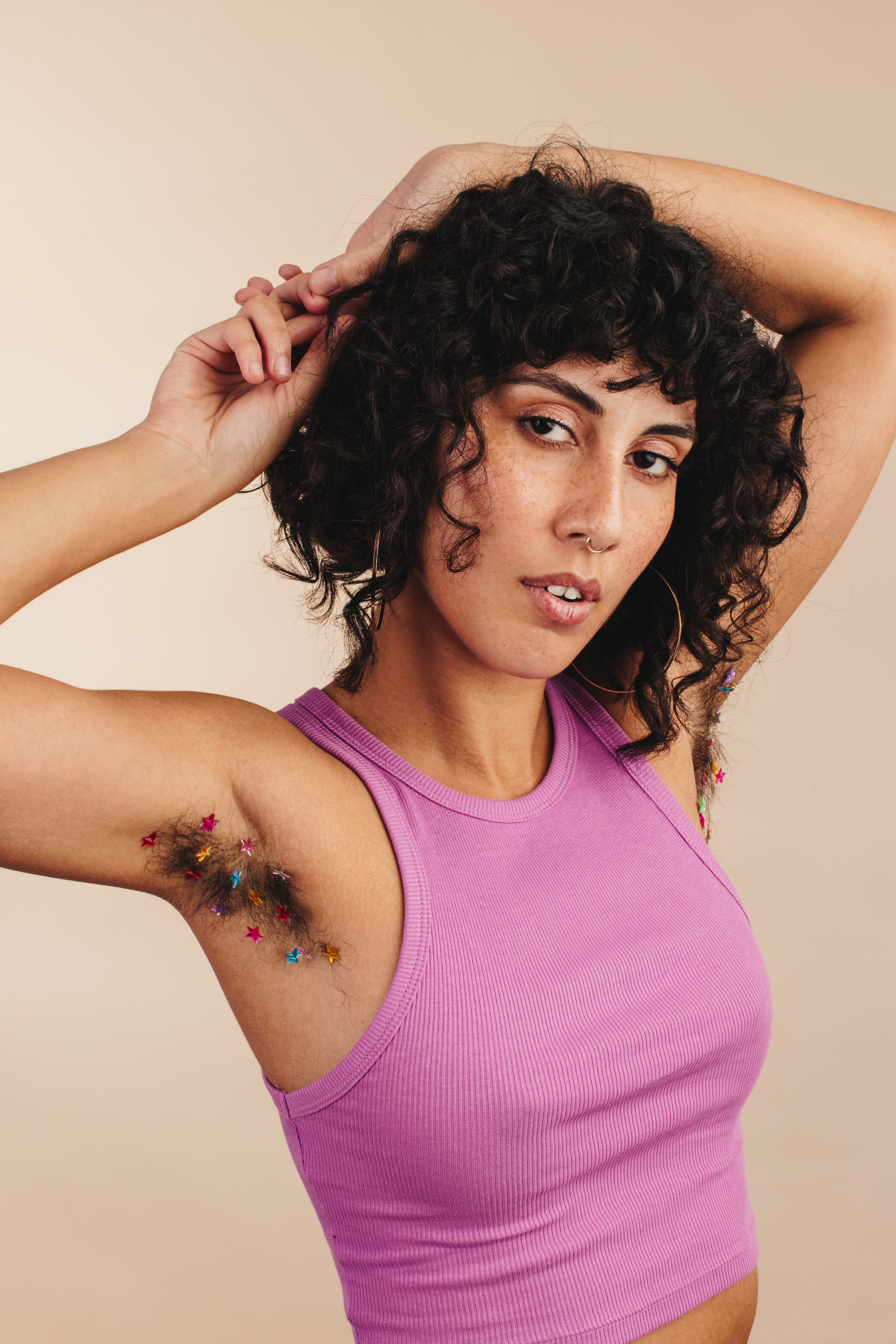 Woman looking at the camera while showing off her confetti-decorated underarms