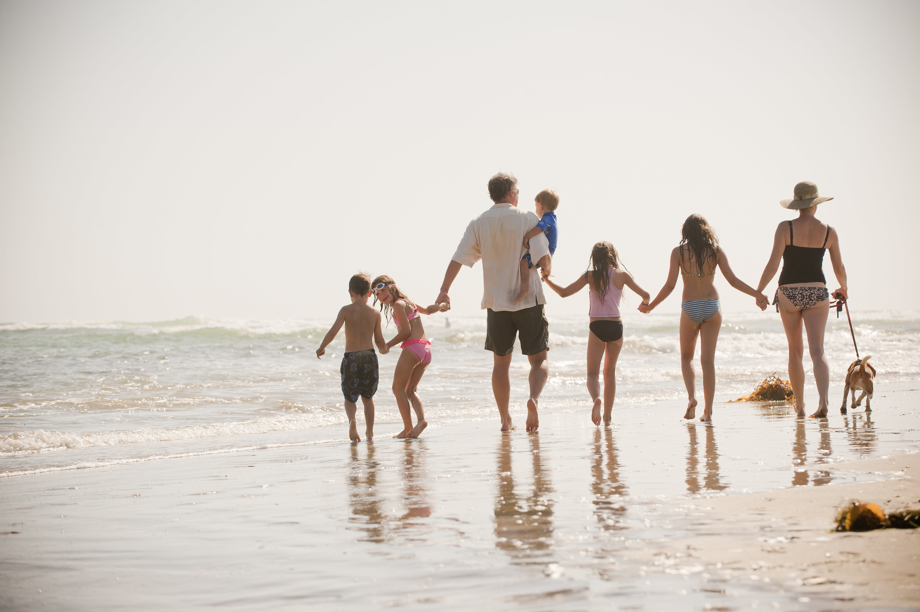 A couple walks along the beach with their five children