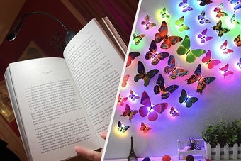A person using a book lamp and a bunch of butterfly lights on a wall