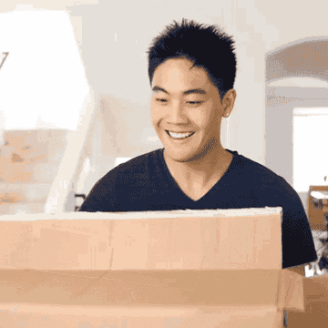 Ryan Higa picking up an empty cardboard box and walking off with it while smiling and nodding