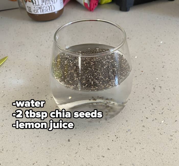 A glass that&#x27;s half full of water with chia seeds floating on top