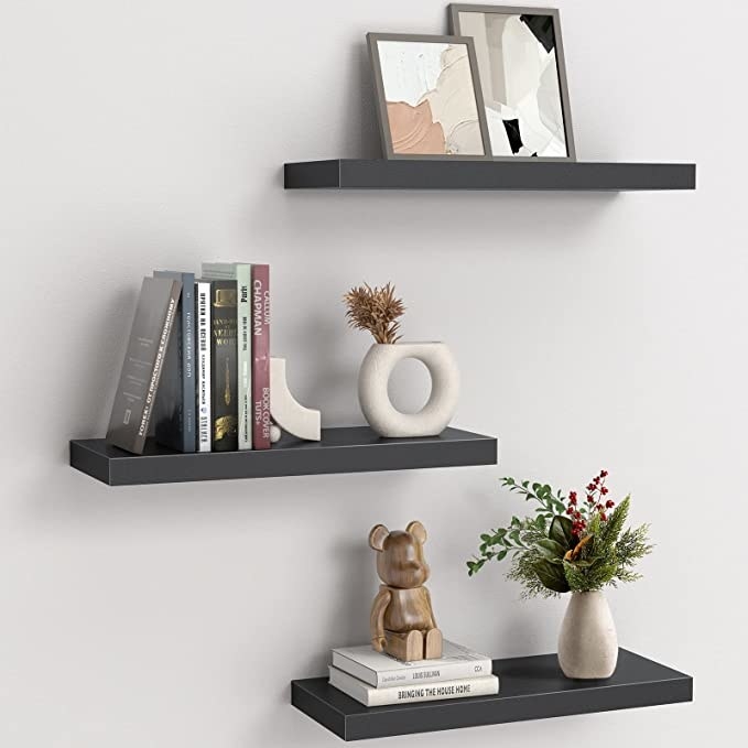 the floating shelves on a wall with trinkets and books on them