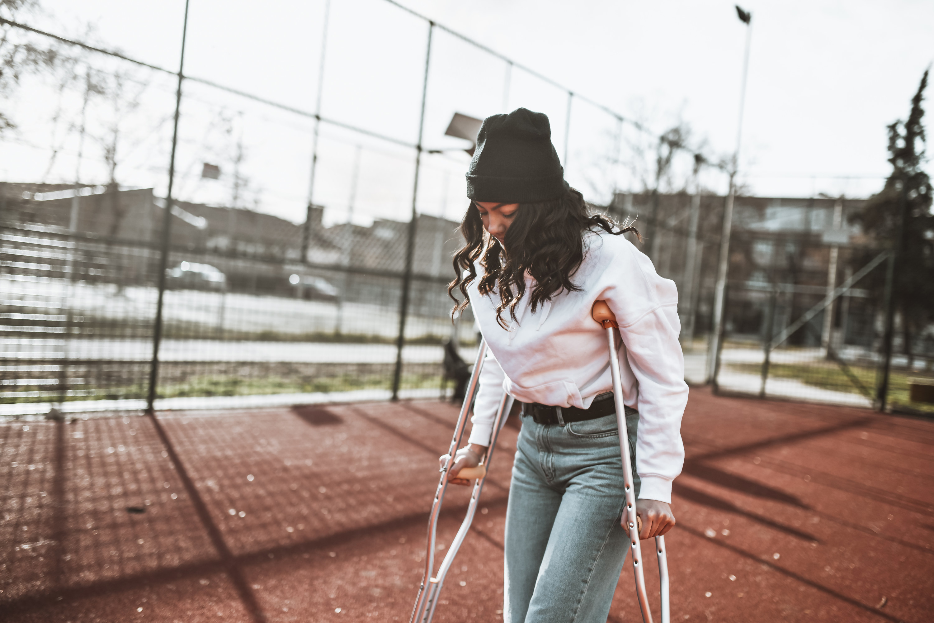A woman on crutches walks by a playground