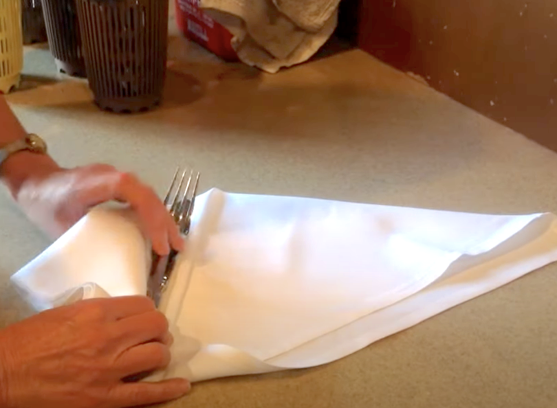 Person rolling up cutlery in a napkin