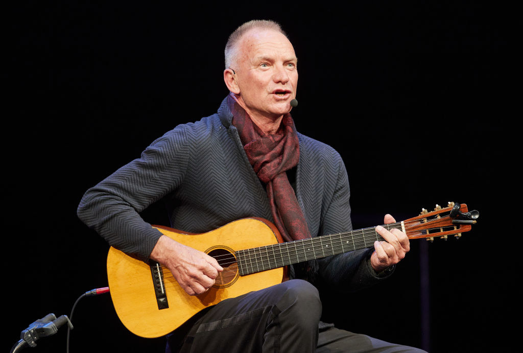 Sting sitting and playing guitar