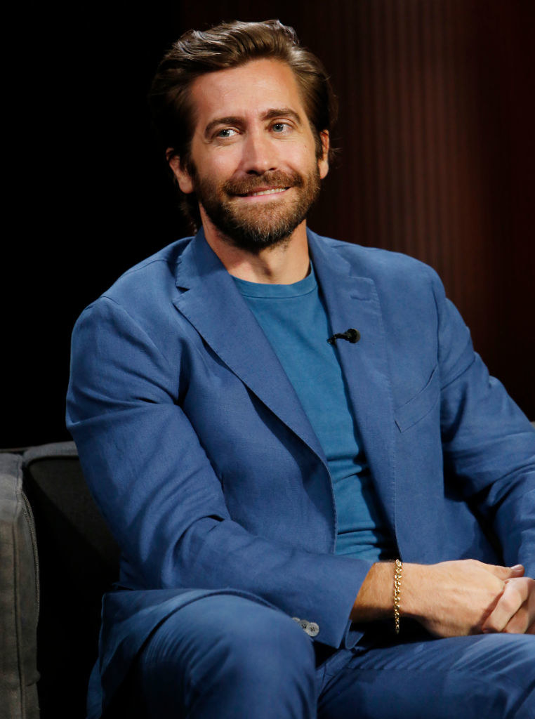 Jake seated and smiling and wearing a suit