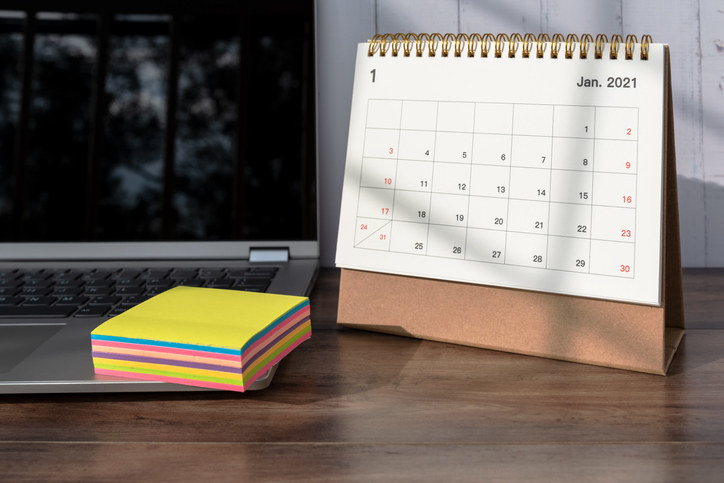 a calendar on a desk with sticky notes and a laptop