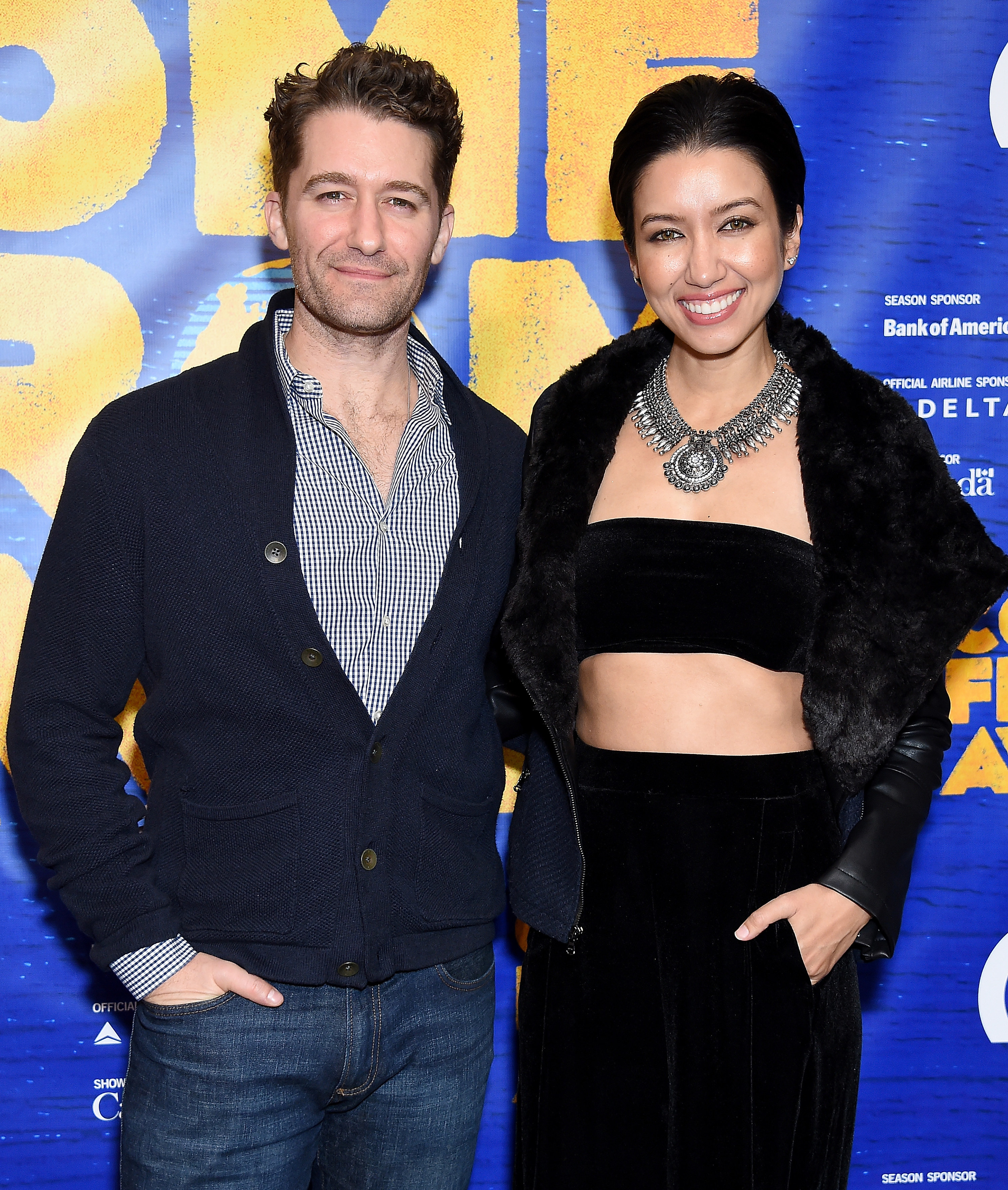 Matthew, in jeans and a sweater, and Renee, in a tube top and furry jacket, smiling on the red carpet