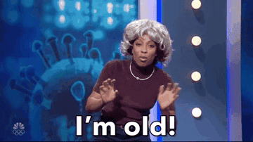 A woman wearing a gray wig and saying &quot;I&#x27;m old!&quot;