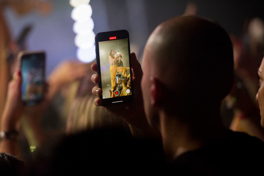 A man watching a concert through his phone