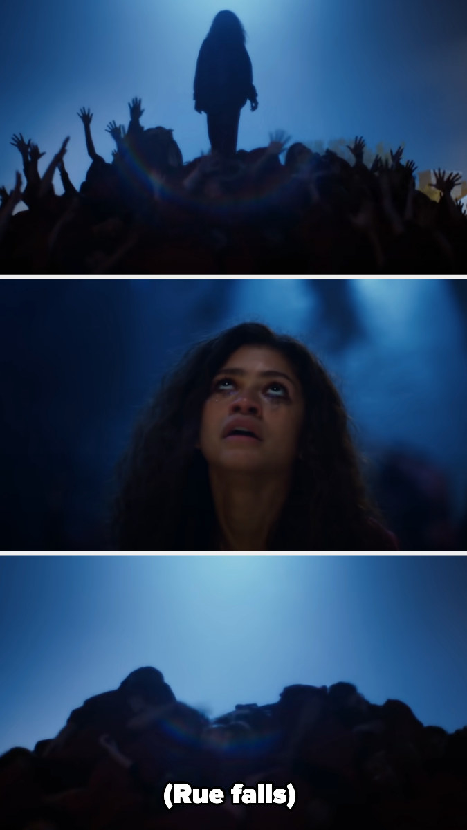 rue climbs up a pile of people, stands there and looks up, then falls