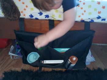 reviewer's photo of a child reaching for the organizer attached to their bunk bed