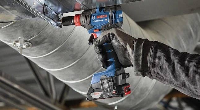 a black and black impact driver with a Phillips head installing a panel