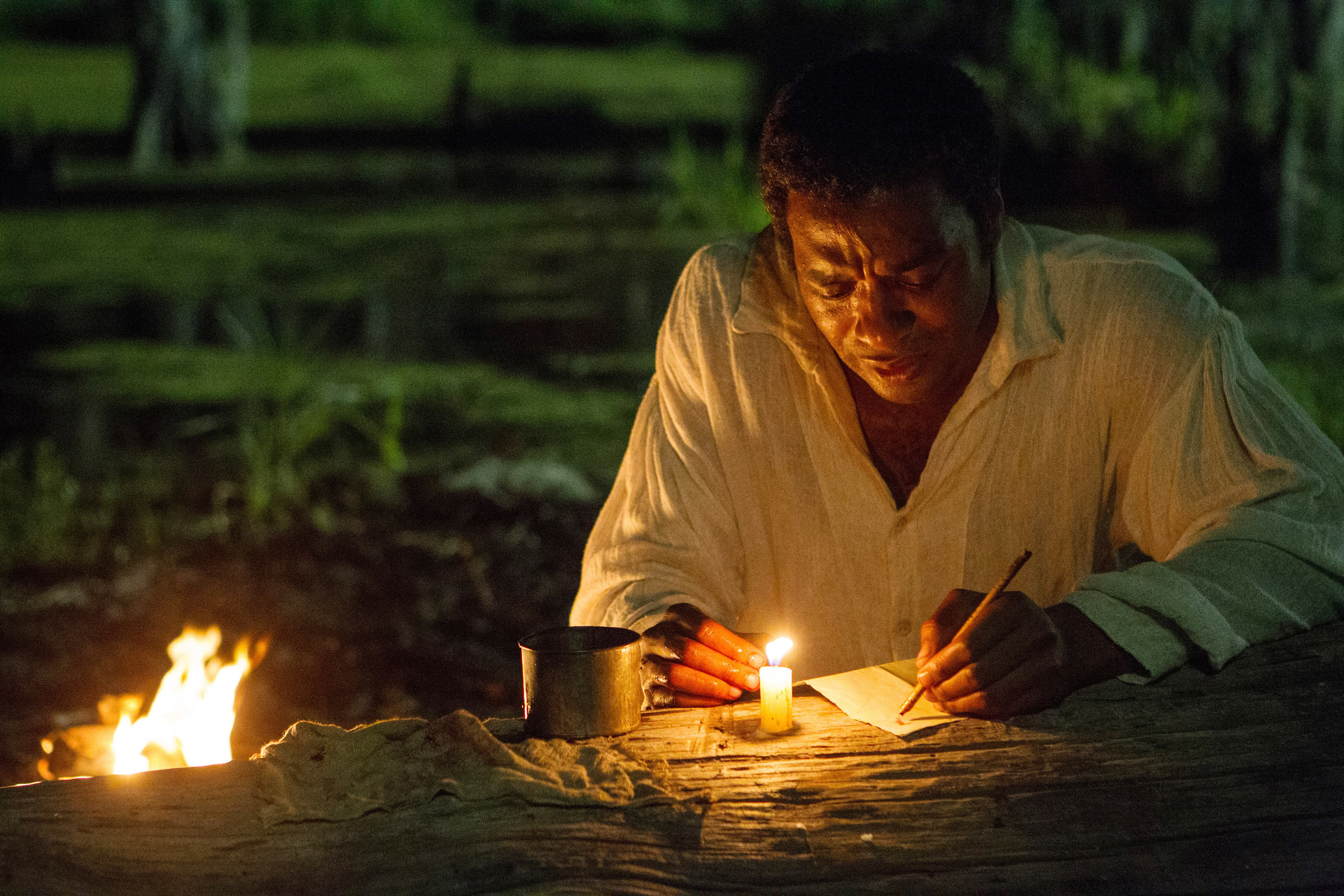 Chiwetel Ejiofor writing a letter by candlelight
