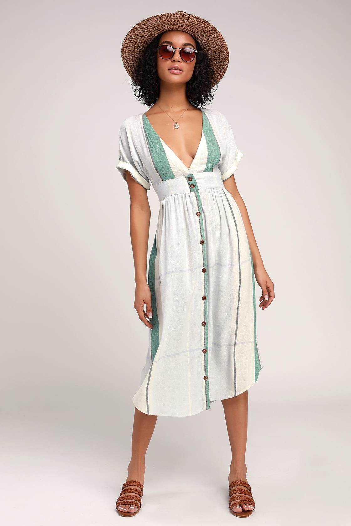 Model is wearing a white and green striped button-up midi dress with brown sandals
