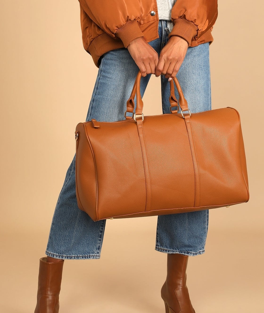 Model is holding the brown leather weekender bag