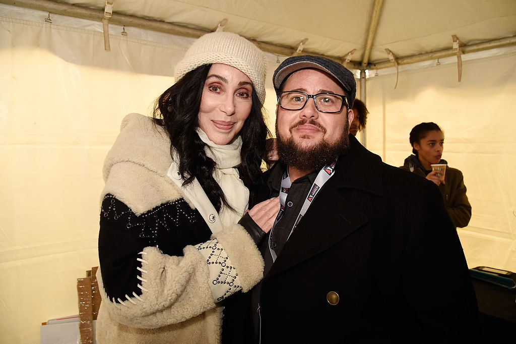 Cher wears a fur coat with a matching beanie and Chaz Bono wears a dark pea coat