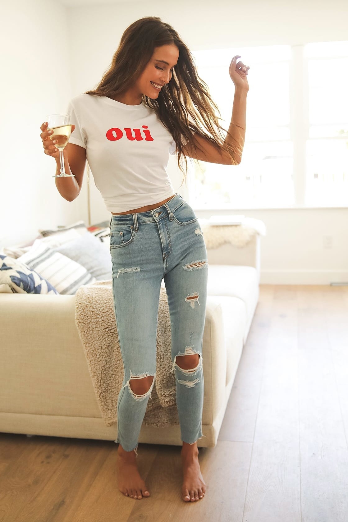 Model is wearing a white T-shirt and light distressed skinny jeans