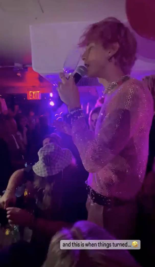 MGK singing into a microphone and holding a champagne glass