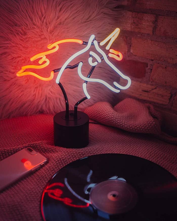 a unicorn-shaped light on a bed next to a vinyl record