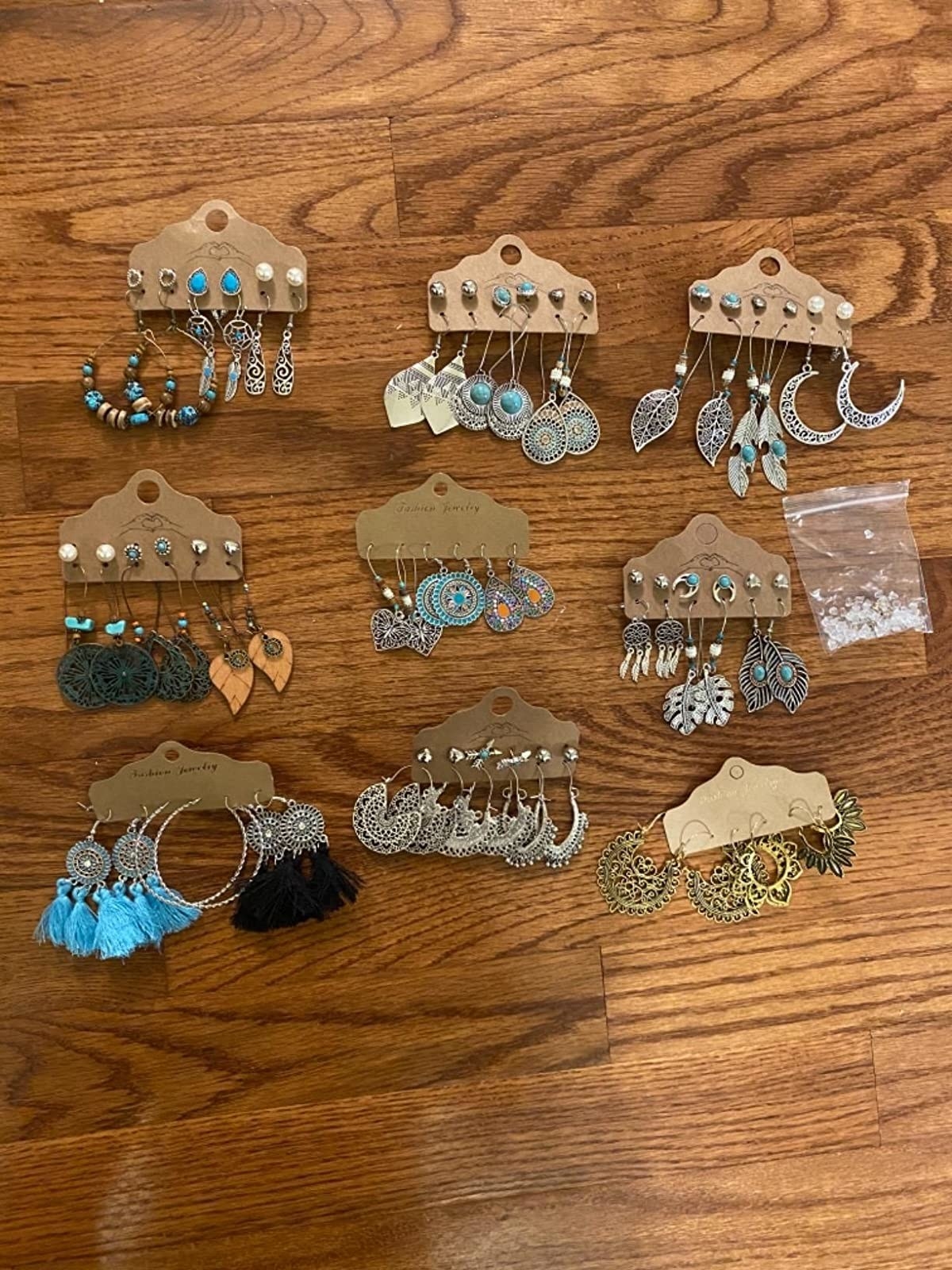 Reviewer&#x27;s photo of some of the dangly and stud earrings in the collection with a bag of extra backs