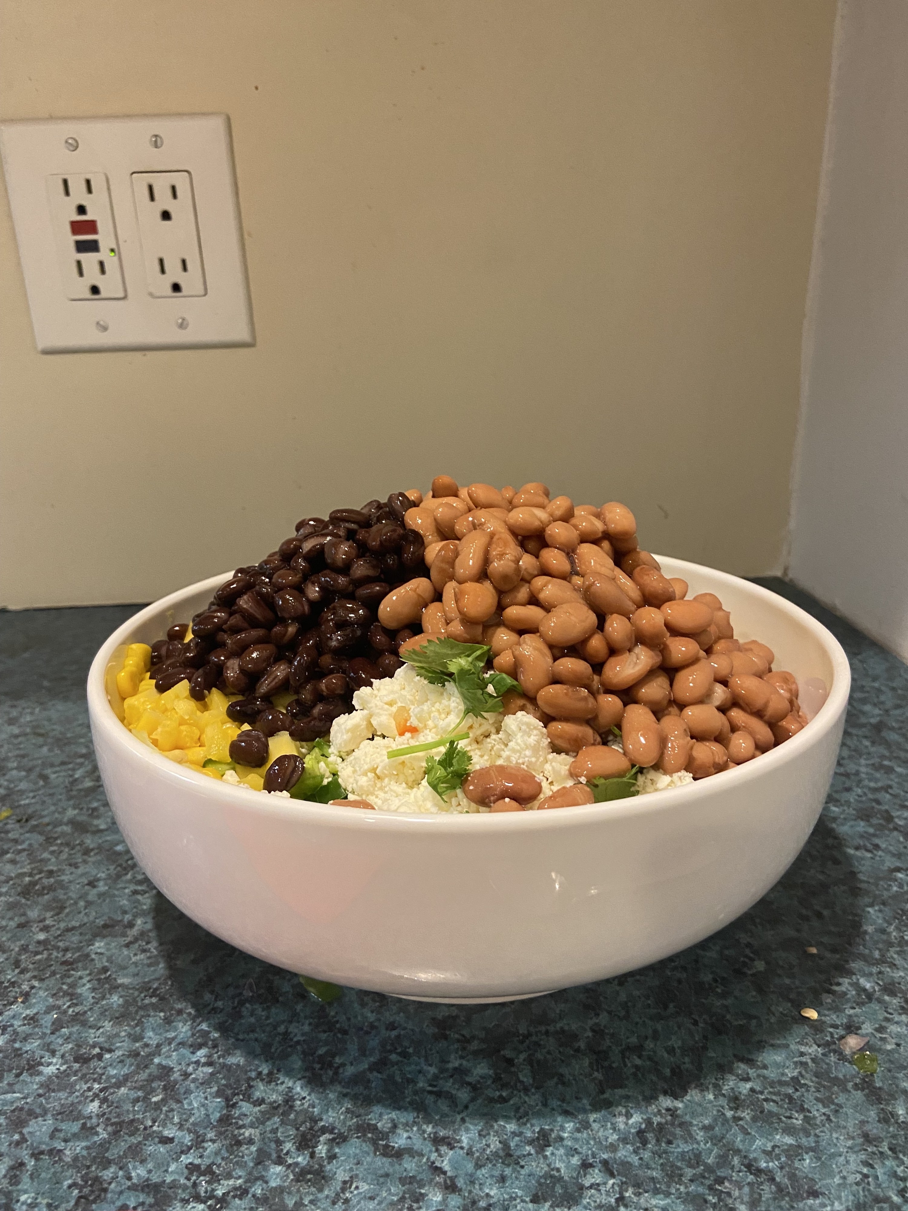 A bowl with beans, veggies, and cheese