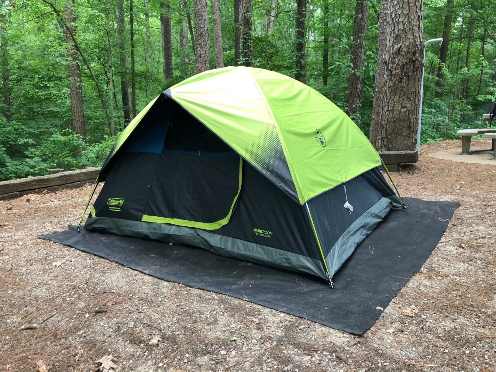 reviewer&#x27;s black tent with green rain fly set up at a campsite in the woods