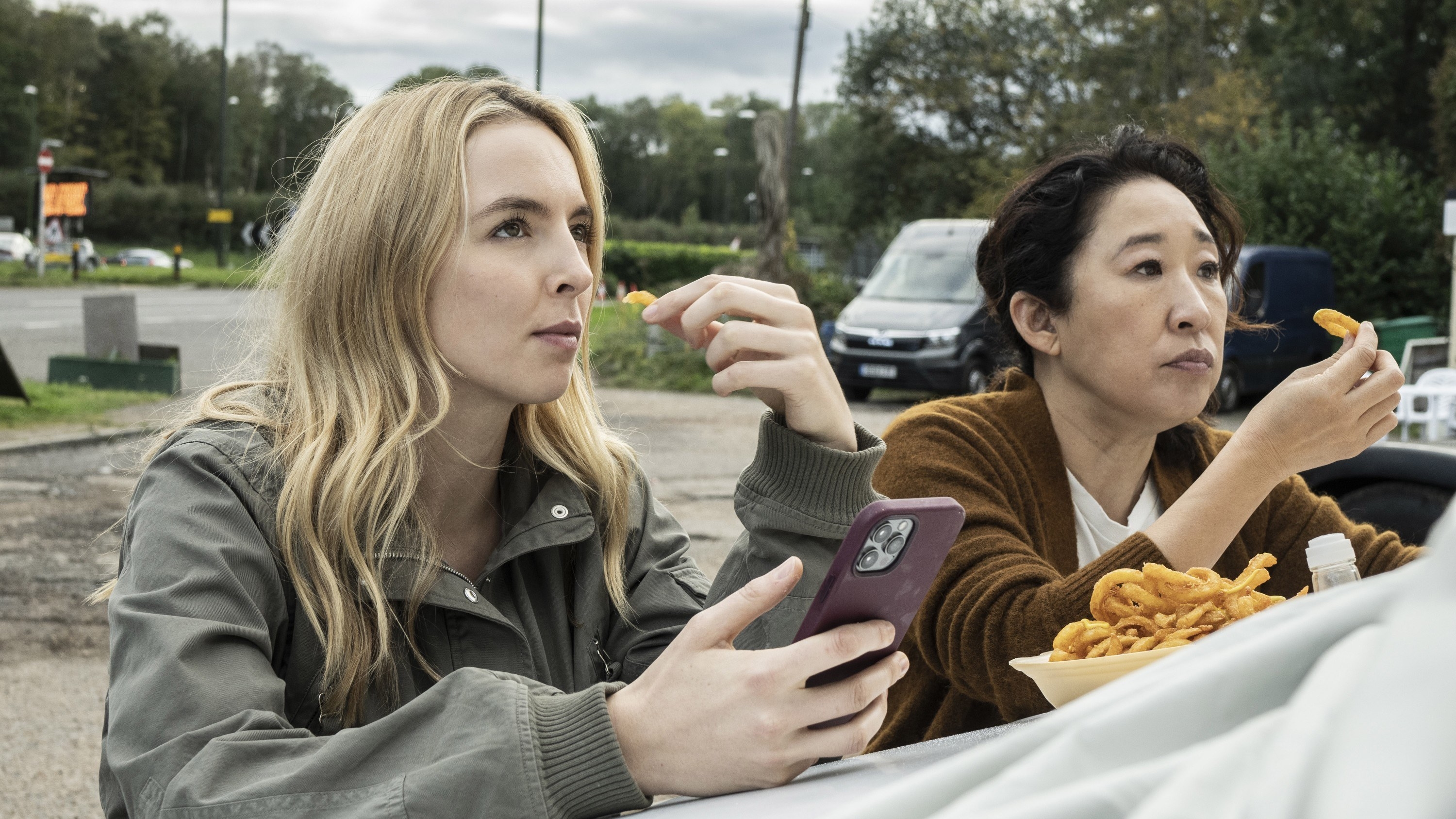 two women eating onion rings in a park