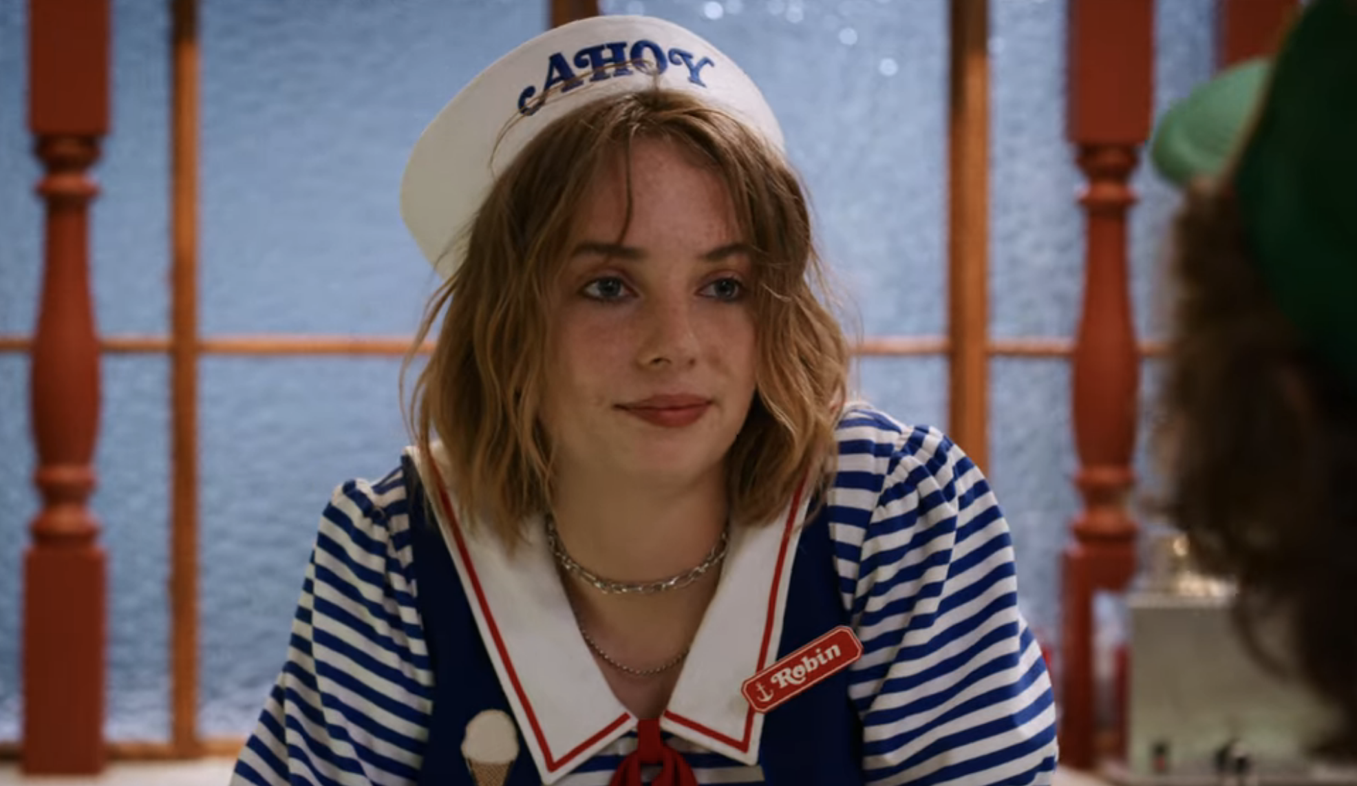 Robin smiles a tight-lipped smile in her Scoops Ahoy uniform