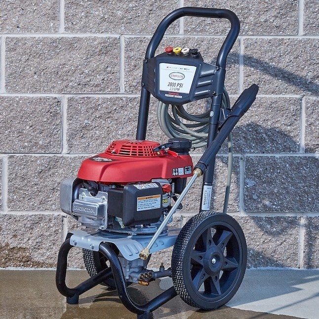 a red and black pressure washer next to a brick wall