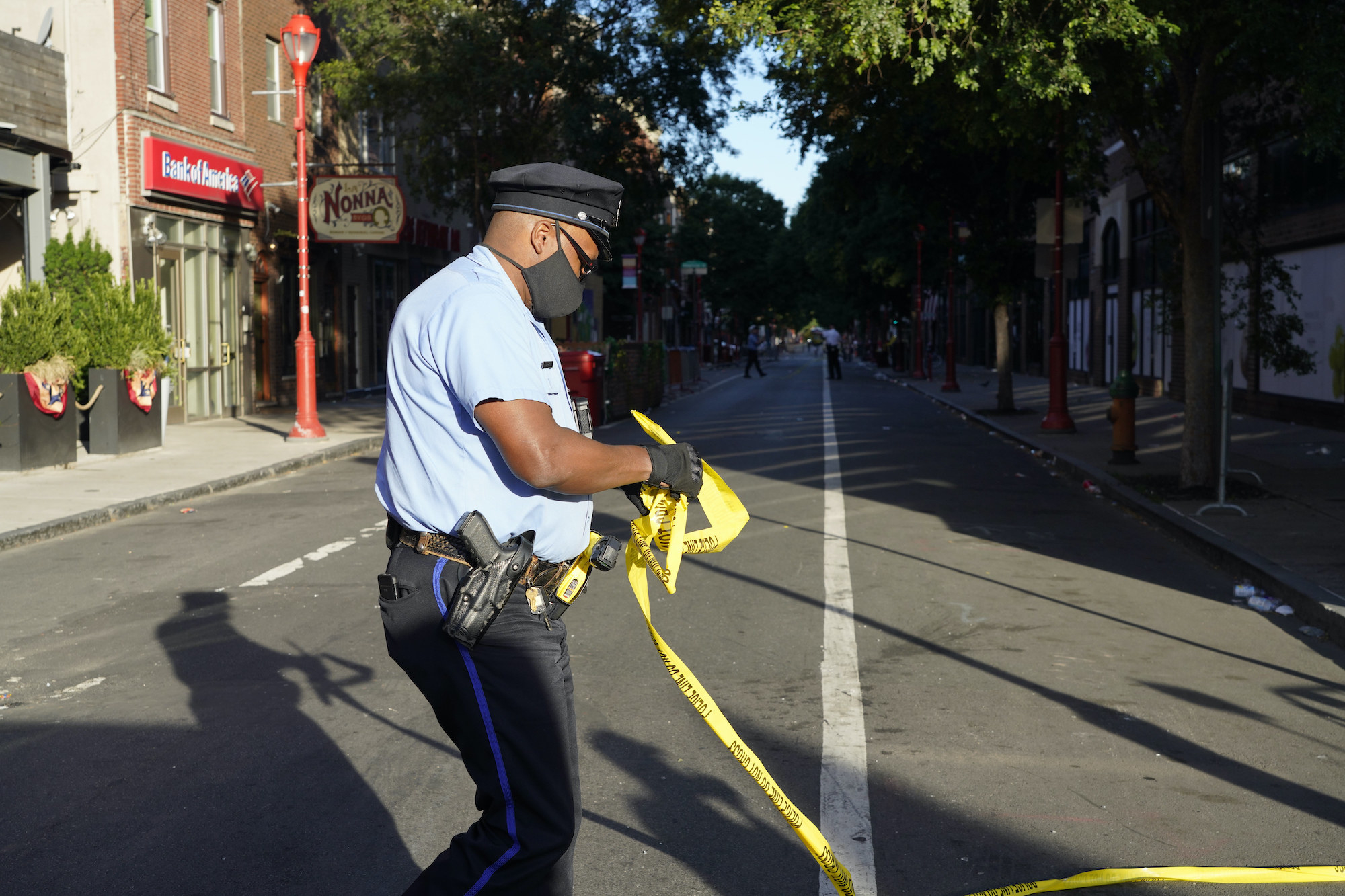 A masked police officer puts up a police line on a street