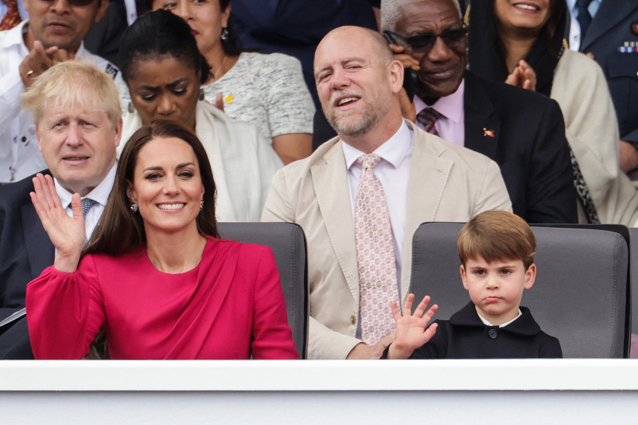 The smiling duchess and a glum-looking Prince Louis waving
