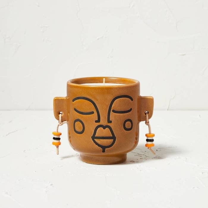 Decorative yellow-brown candle with face, ears, and earrings