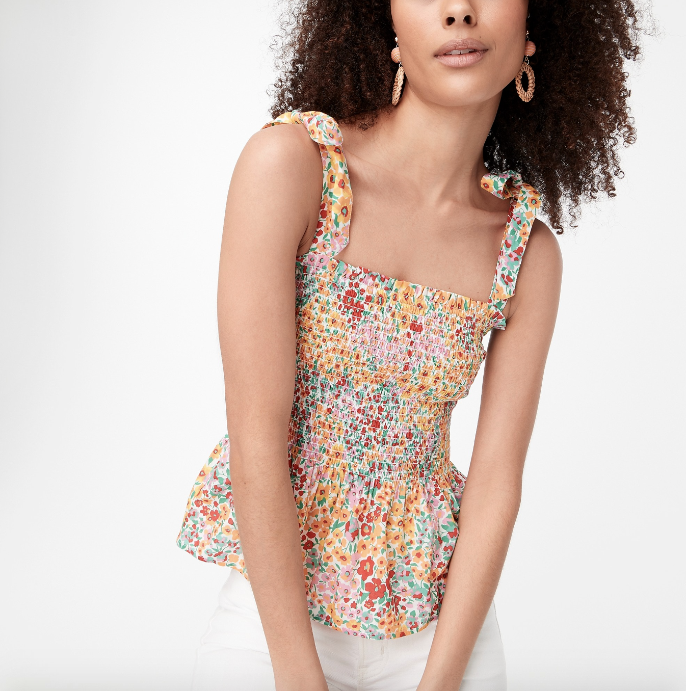 model in floral-print sleeveless top and white pants