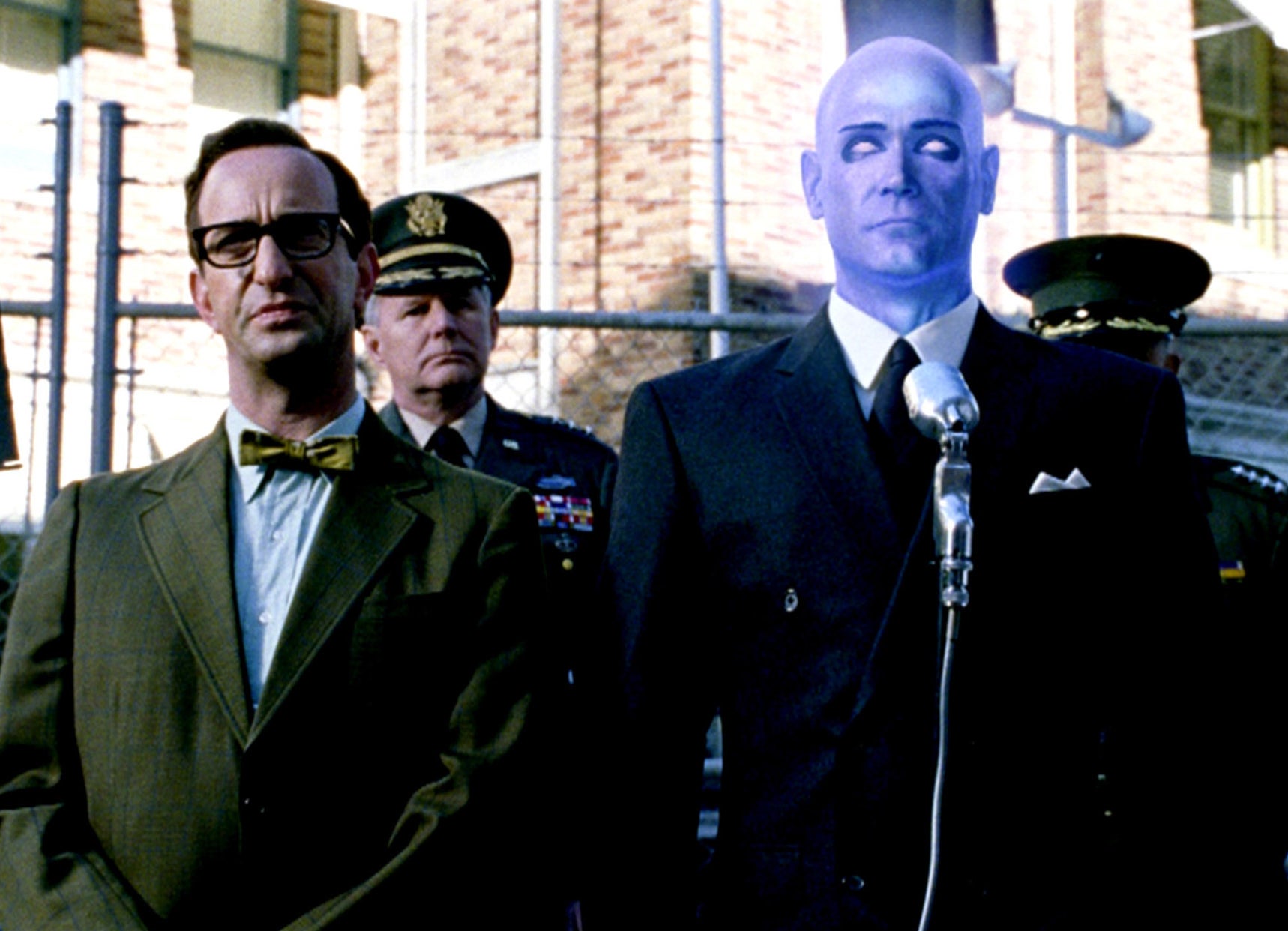 blue, glowing Dr. Manhattan standing at a press conference in watchmen