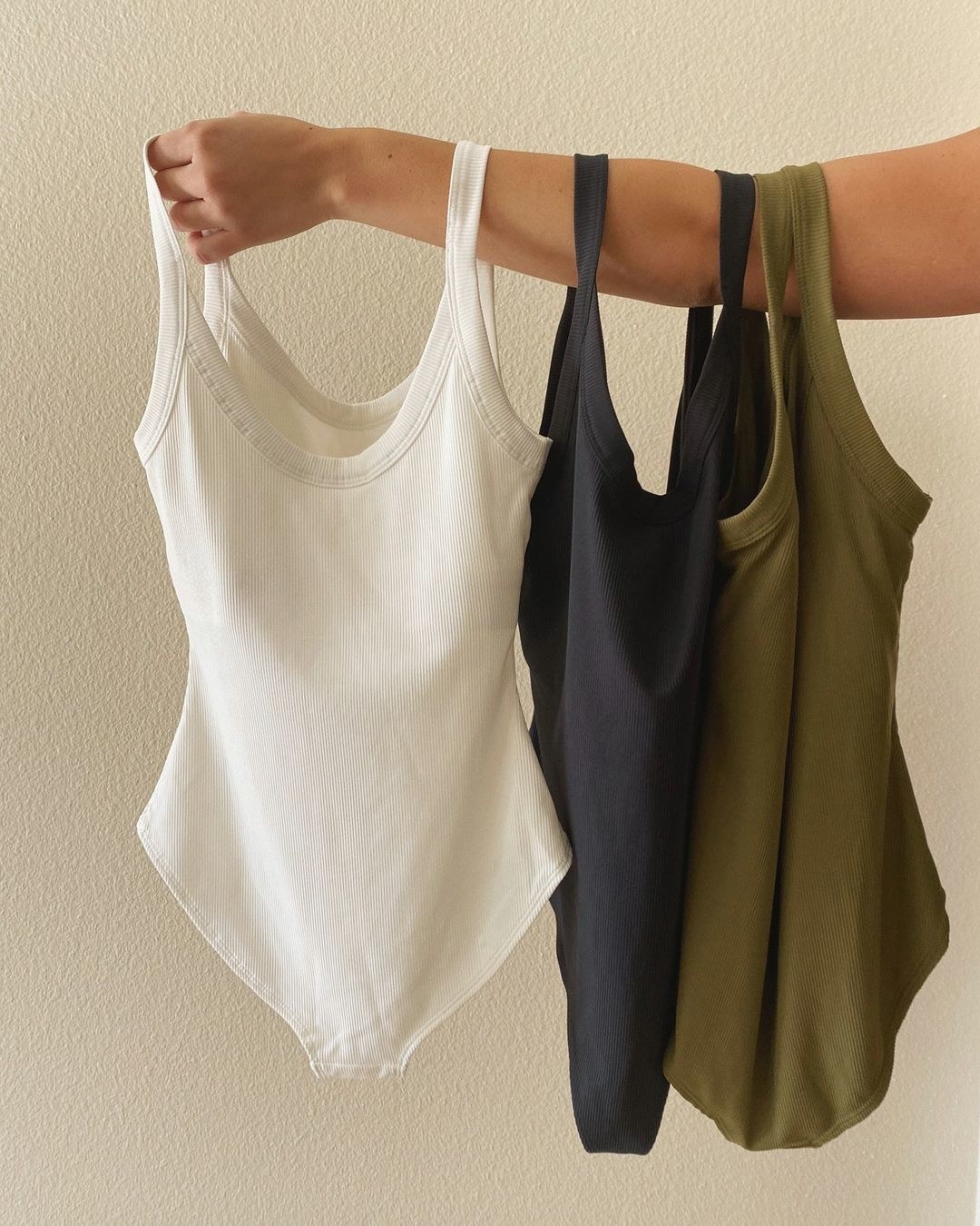 Three bodysuits hanging off of an arm