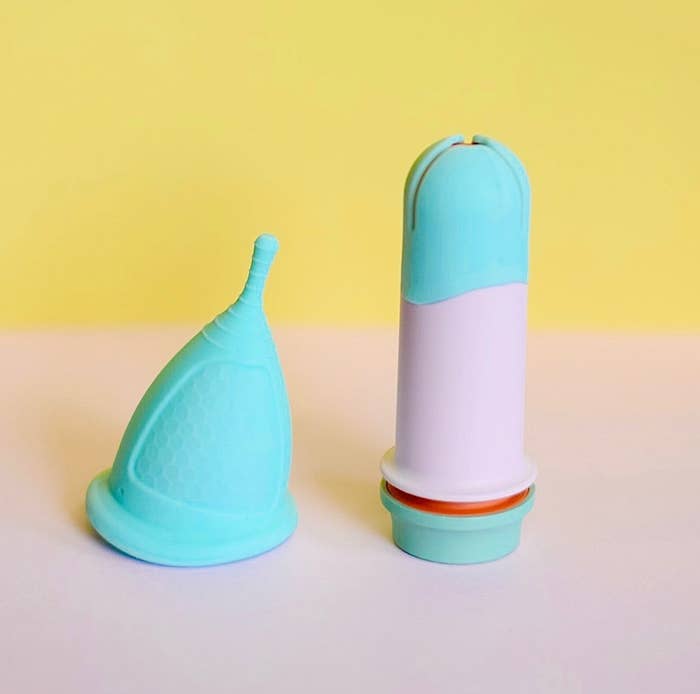 Sunny menstrual cup on the right with the applicator standing on the left