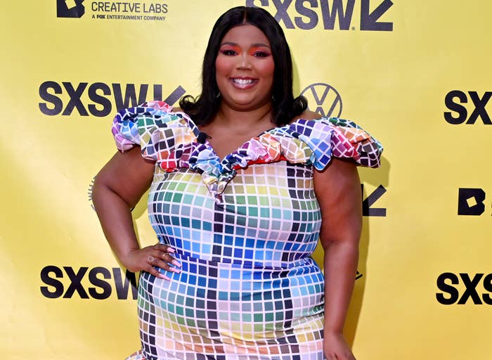 Lizzo on the red carpet and smiling with hand on hip