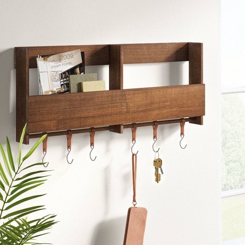 An image of a wooden shelf with leather hooks