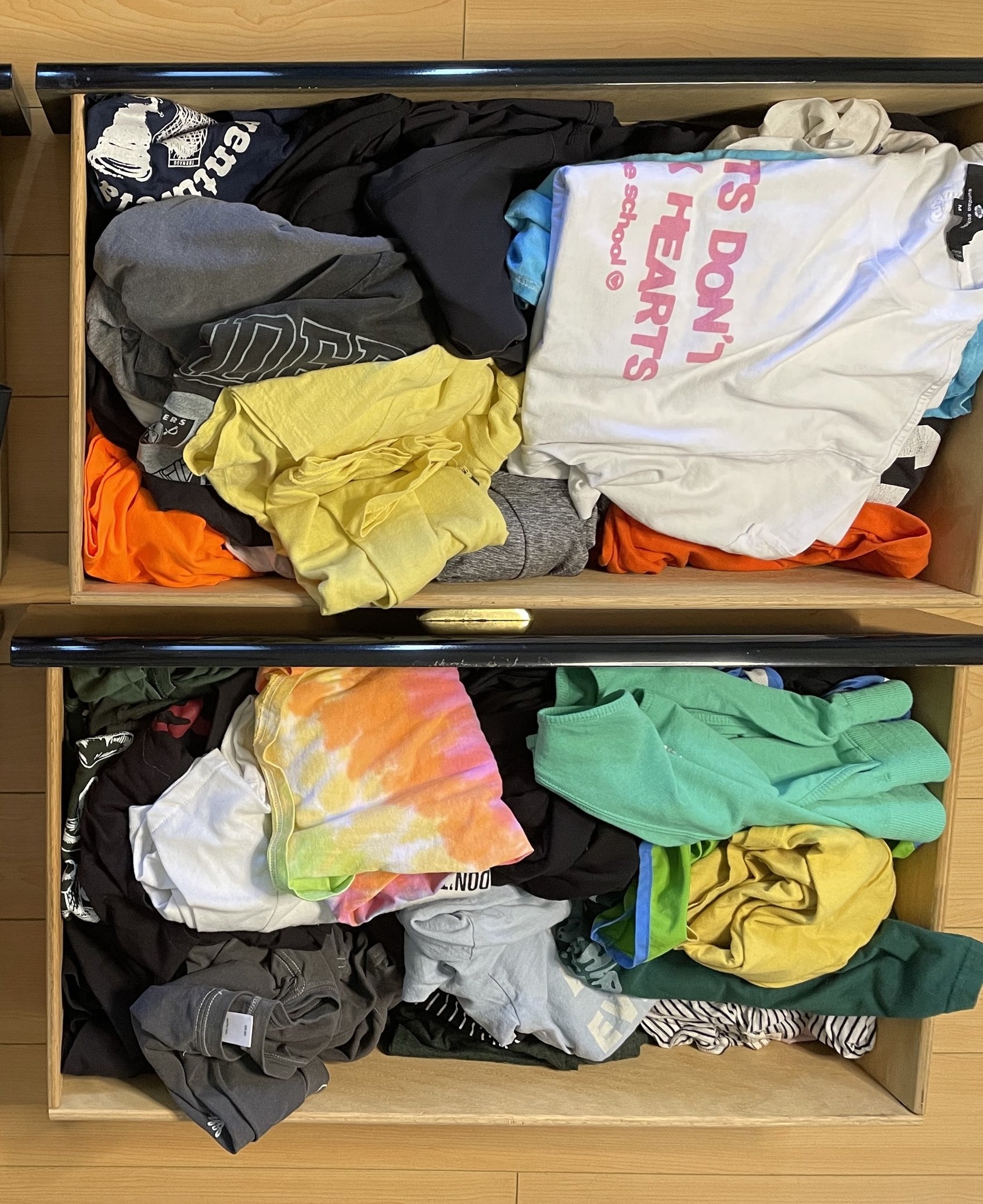 A top-down shot of two t-shirt drawers that hold shirts scattered randomly