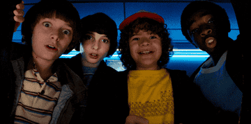 Will, Mike, and Lucas cheering on Dustin as he plays &quot;Dragon&#x27;s Lair&quot; in &quot;Stranger Things&quot;