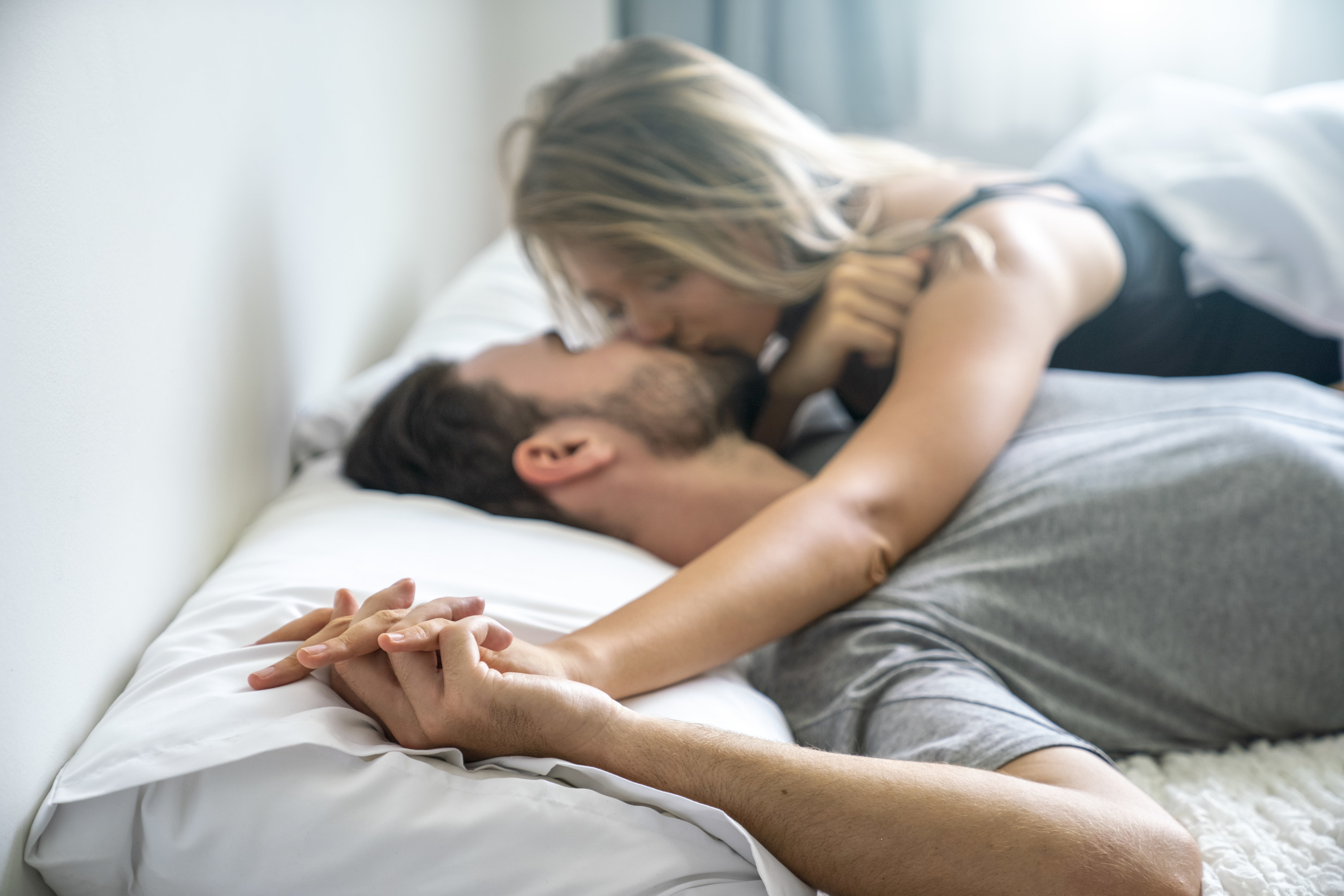 A man and a woman kissing in bed
