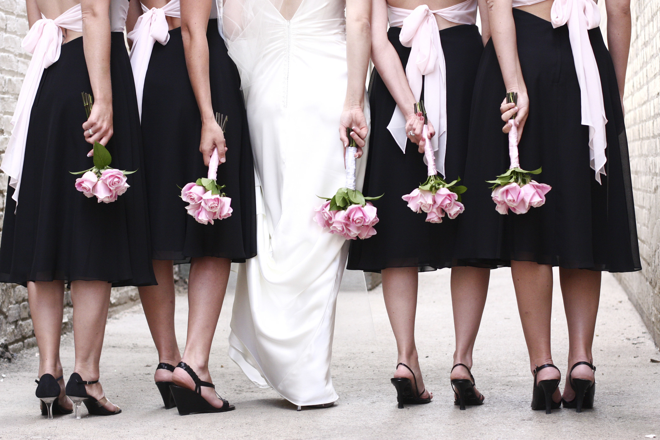 bride and bridesmaids photo from the waist down showing roses in their hands