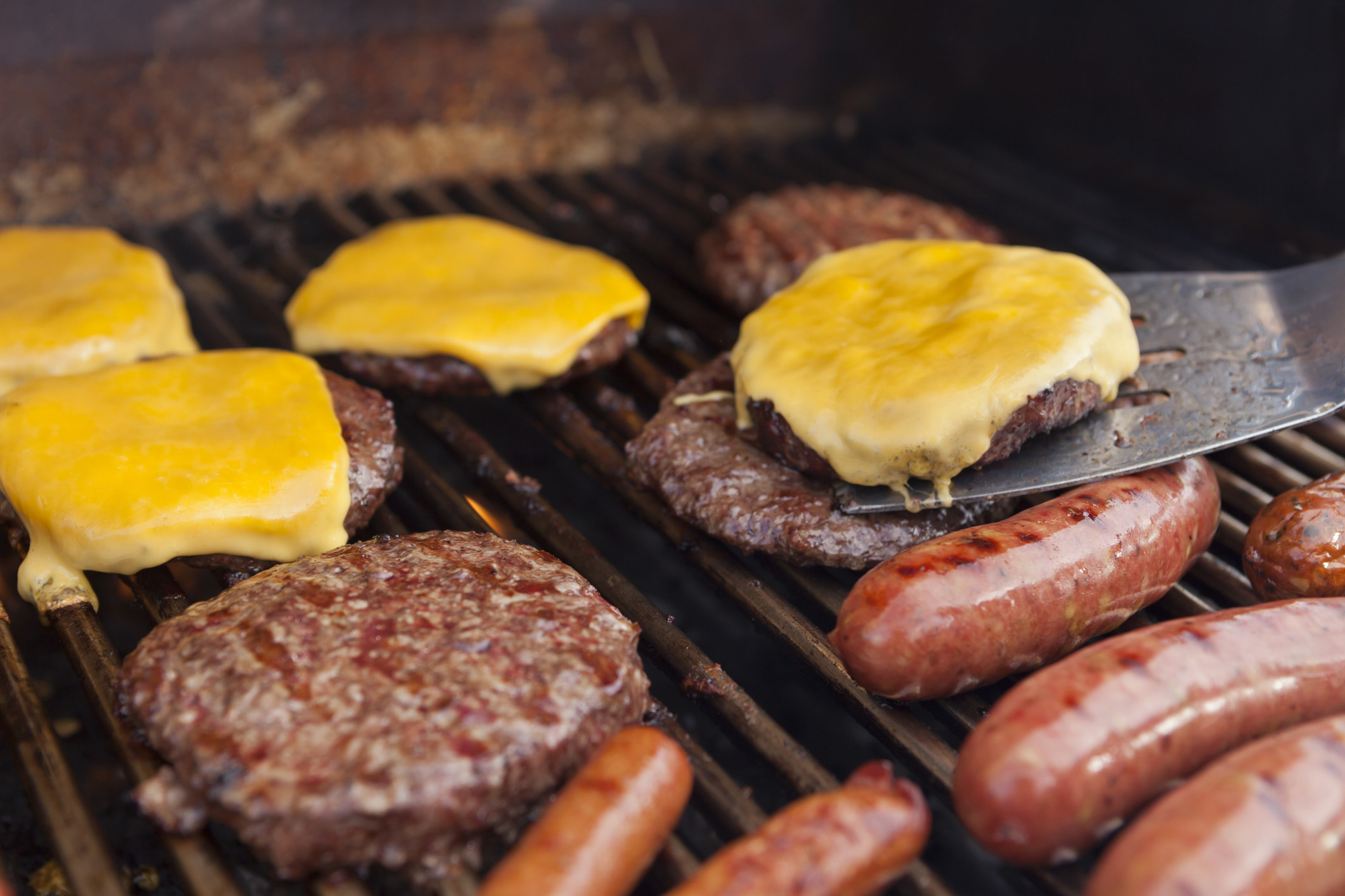 Burgers, cheeseburgers, sausage, and franks on a grill