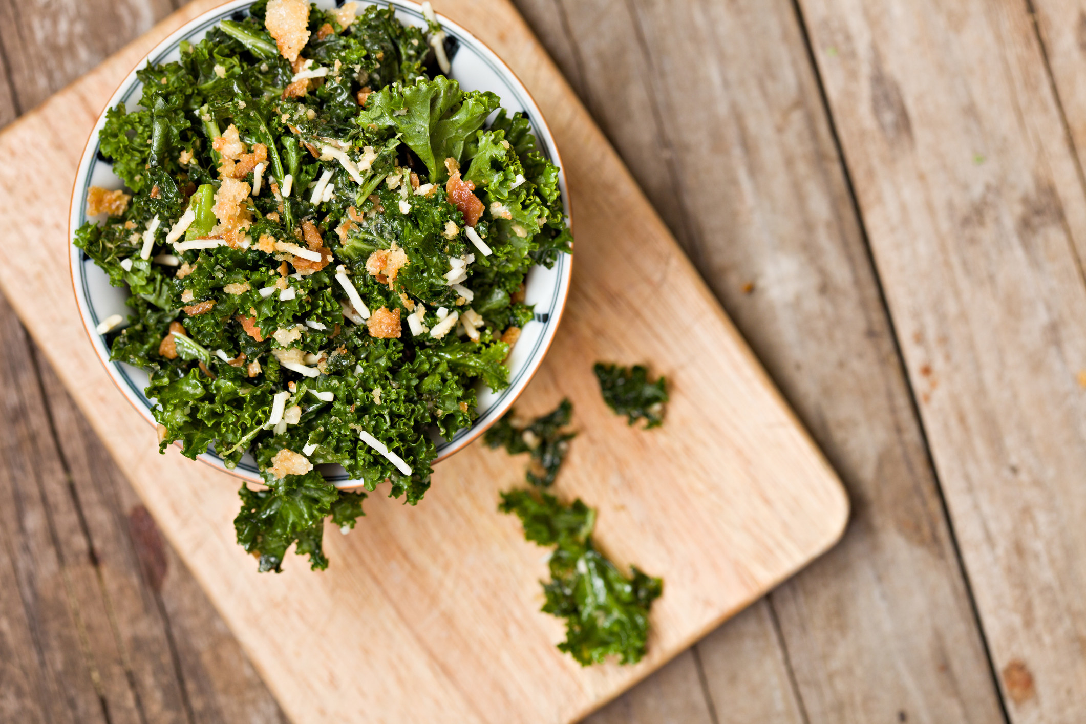 A bowl of kale salad on a cutting board